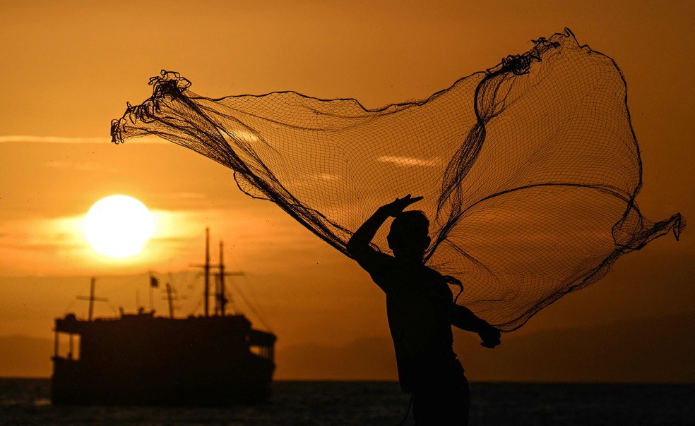 Homem prepara a rede de pesca em Juan Griego, cidade em Isla Margarita, no Caribe venezuelano, conhecida por seu belo pôr do sol — Foto: Juan Barreto / AFP
