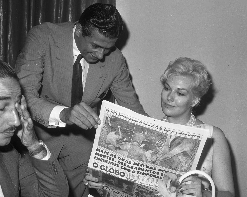 Durante almoço no restaurante do jornal, o colunista Ibrahim Sued mostra um exemplar do GLOBO a Kim Novak — Foto: Acervo O GLOBO