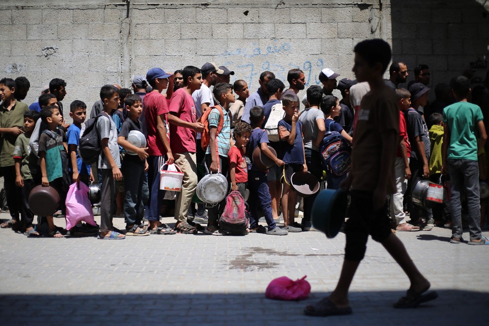 Civis se amontoam em busca de alimentos do lado de fora de centro de distribuição de ajuda no campo de refugiados de Nuseirat, na Faixa de Gaza — Foto: Eyad BABA / AFP