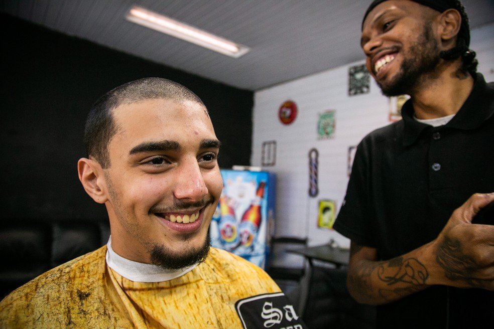 O barbeiro Felipinho corta o cabelo de Luciano Ferreira — Foto: Rebecca Alves/Agência O Globo