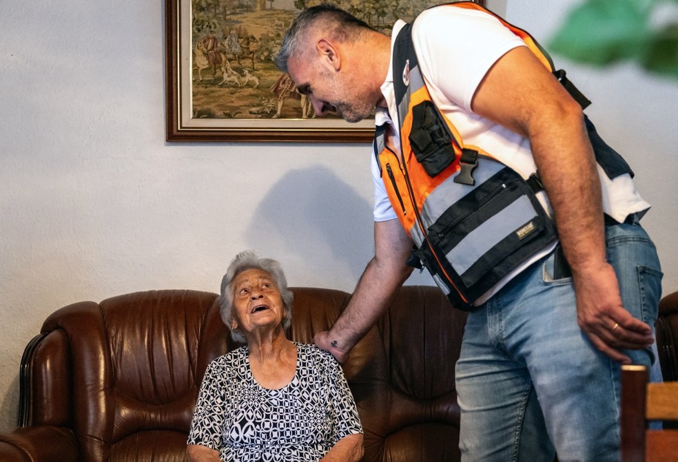 Maria Rosel, de 94 anos, conversa com o coordenador municipal da Proteção Civil, Filipe Almeirante, enquanto se refugia em sua casa devido às altas temperaturas que atingem a região, em 3 de julho de 2026, em Vale de Figueira, Santarém, Portugal — Foto: HENRIQUE CASINHAS / AFP