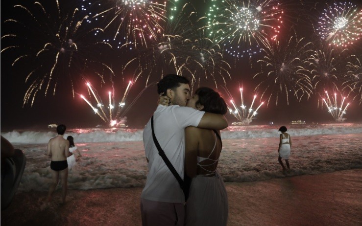Um beijo para comemorar a chegada de 2024 tendo a tradicional queima de fogos como fundo. Foto de Gabriel de Paiva