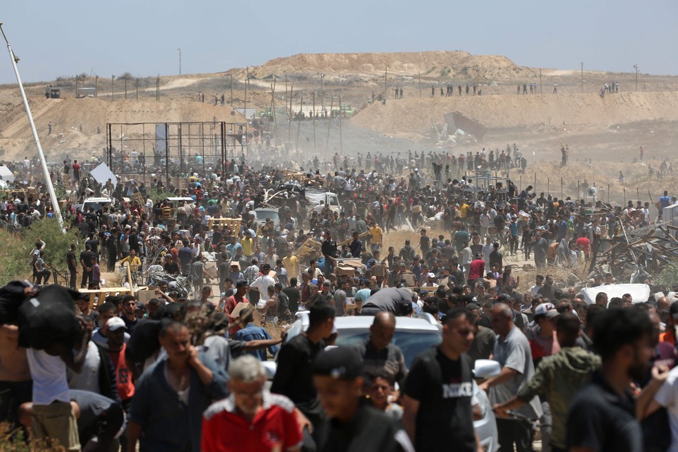 Palestinos deslocados carregam suprimentos na região central da Faixa de Gaza — Foto: Eyad Baba/AFP