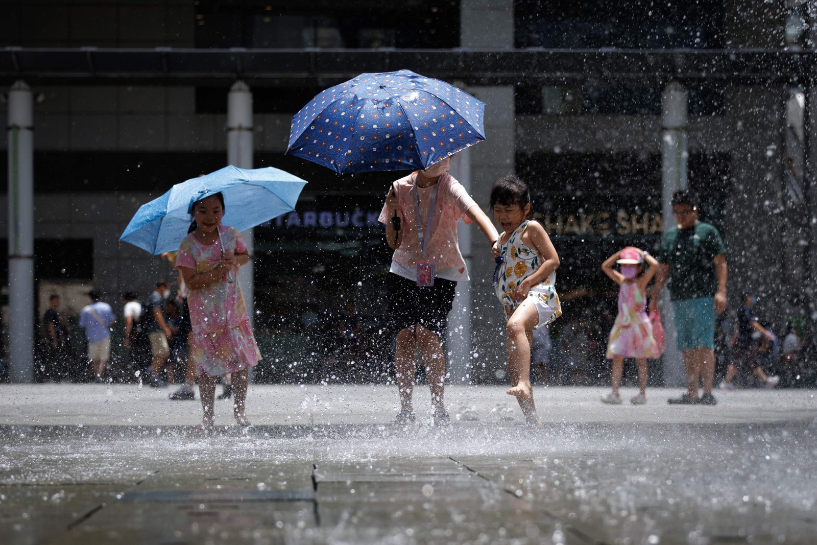 Crianças se refrescam em uma fonte de água durante uma onda de calor em Hong Kong — Foto: May JAMES / AFP