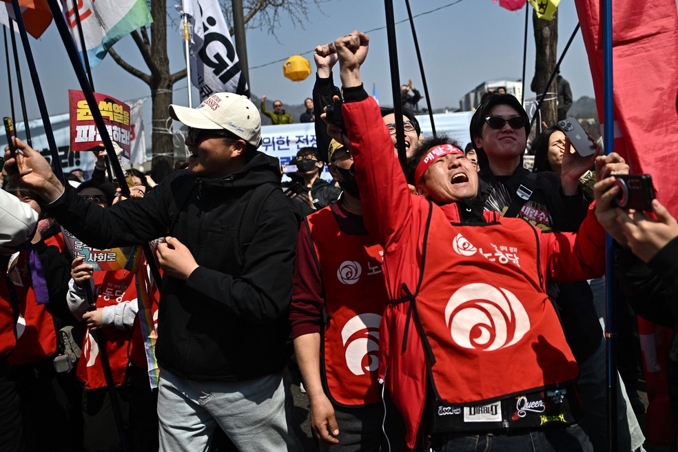 Manifestantes contrários ao presidente afastado Yoon Suk-yeol comemoram a confirmação do impeachment pela Corte Constitucional em Seul — Foto: Pedro Pardo / AFP