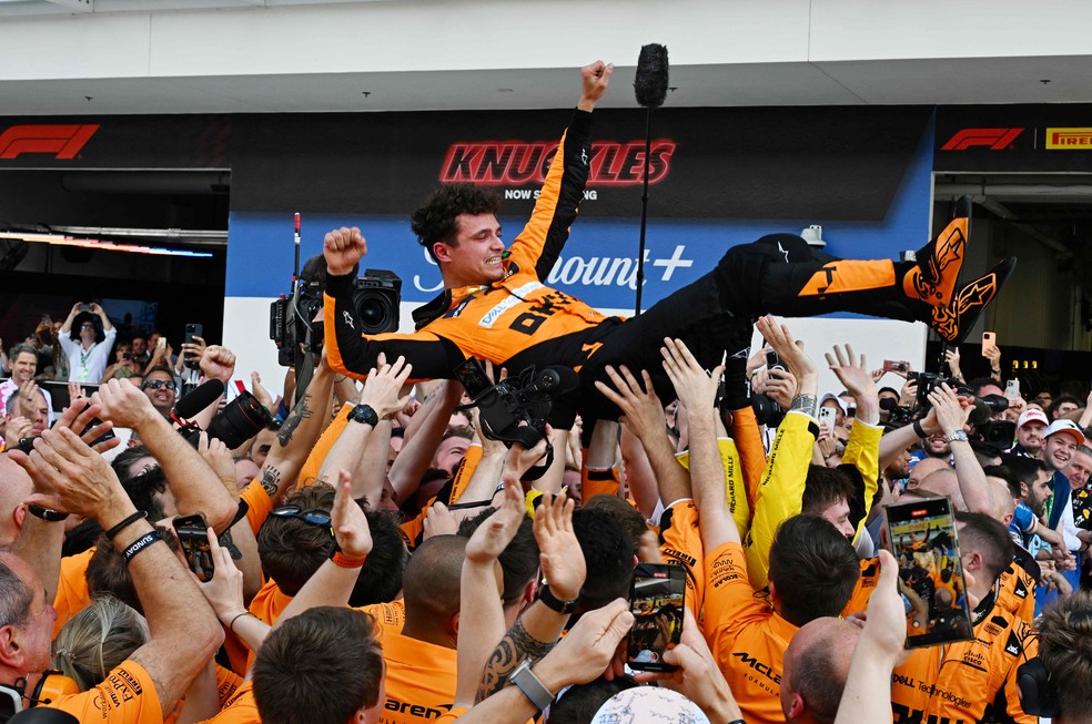 O piloto britânico da McLaren, Lando Norris, é jogado para o ar enquanto sua equipe comemora — Foto: Giorgio Viera - AFP