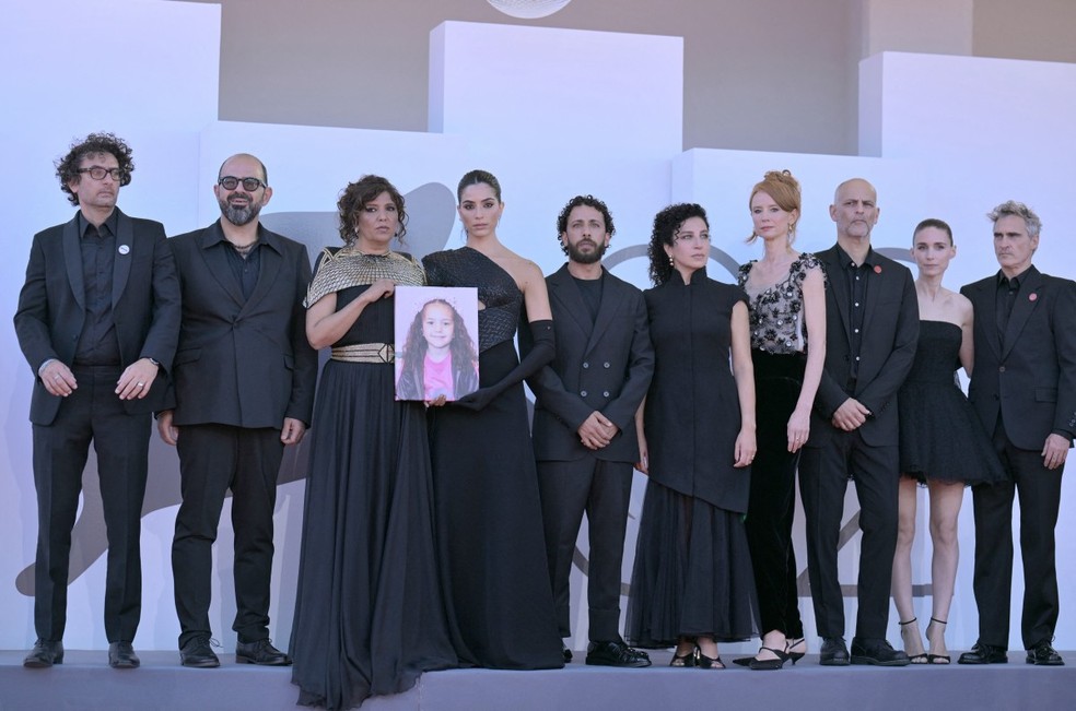 "The Voice of Hind Rajab", apresentado no Festival de Cinema de Veneza. A partir da esquerda, o produtor tunisiano Nadim Cheikhrouha, o ator israelense Amer Hlehel, a diretora tunisiana Kaouther Ben Hania, a atriz Saja Kilani, o ator Motaz Malhees, a atriz Clara Khoury, os produtores Odessa Rae e Jim Wilson os atores Rooney Mara e Joaquin Phoenix — Foto: Tiziana Fabi/AFP