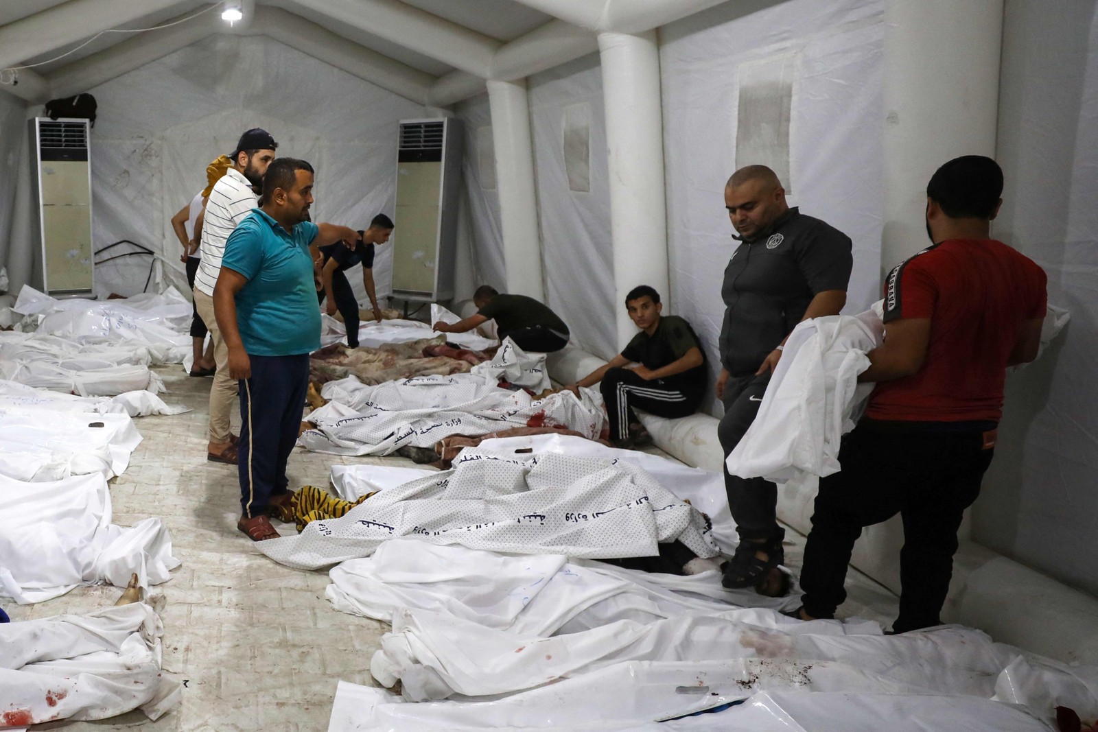 Pessoas carregam corpos de palestinos mortos em ataques aéreos israelenses no hospital Ahli Arab, no centro de Gaza — Foto: Dawood NEMER/AFP