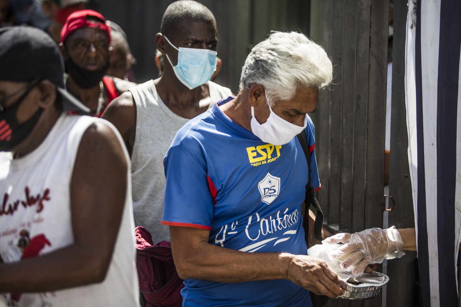 Homem usando máscara de proteção recebe refeição no Centro do RioAgência O Globo
