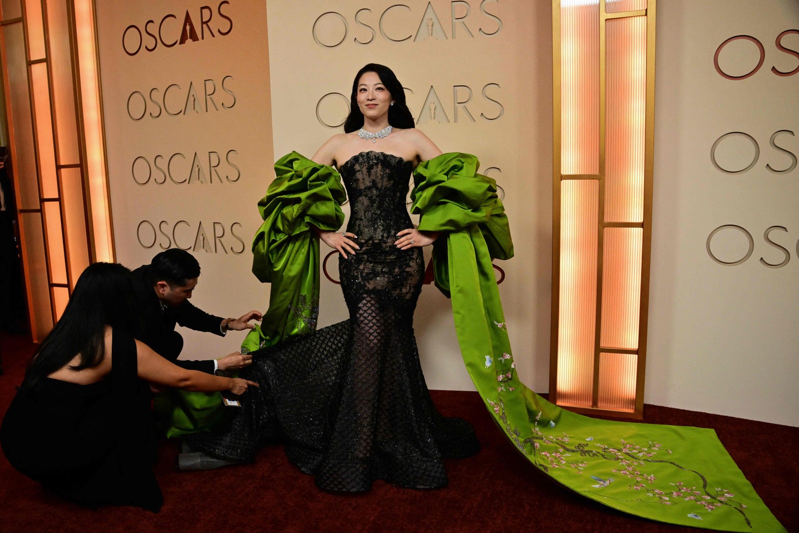 A atriz e cantora Arden Cho tem o vestido ajustado por um membro da equipe momentos antes de posar para fotos no tapete vermelho do Academy Awards, no Dolby Theatre, em Hollywood, na Califórnia. — Foto: Frederic J. Brown / AFP