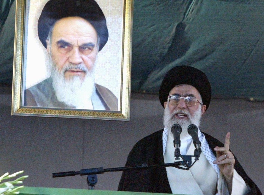 Ali Khamenei, líder supremo do irã, em discurso em junho de 2003, ao lado de imagem do aiatolá Ruhollah Khomeini