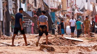 Pessoas verificam uma área danificada por inundações repentinas em Derna, no leste da Líbia — Foto: AFP