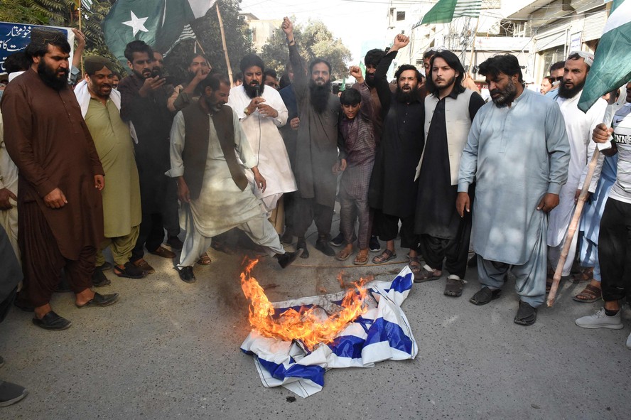 Manifestantes queimam uma bandeira de Israel durante um comício para mostrar solidariedade aos palestinos, em Quetta