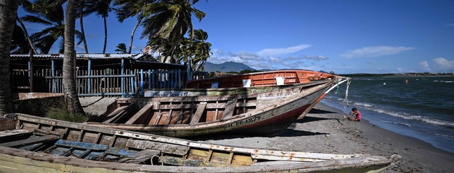 Criança brinca perto de embarcações abandonadas na praia El Yaque, em Isla Margarita, a 'pérola do Caribe' da Venezuela — Foto: Juan Barreto / AFP