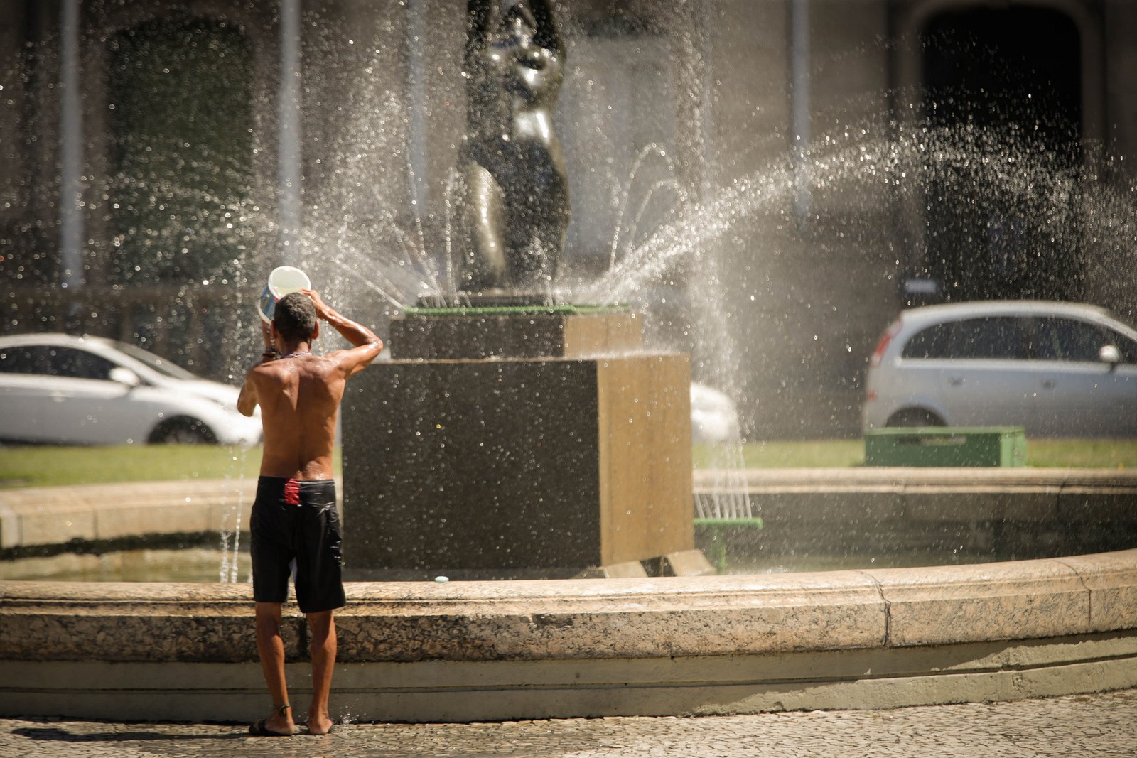Homem usa água do chafariz para se refrescar, no centro do Rio de Janeiro — Foto: Roberto Moreyra/Agência O Globo