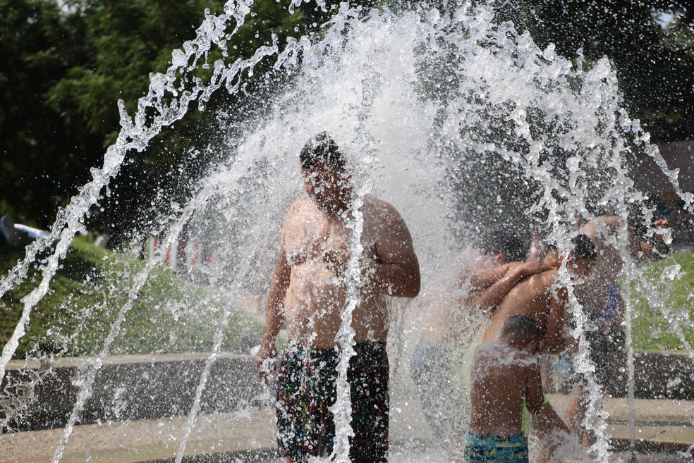 Pessoas se refrescam sob fontes de água na área de lazer Madri por conta da primeira onda de calor do verão. — Foto: Thomas Coex / AFP