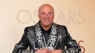 O empresário Kevin O'Leary ajeita um colar cravejado de diamantes com um raro cartão colecionável “Logoman” de basquete, com pedaços de camisas usadas em jogos e autógrafos de Michael Jordan e Kobe Bryant, enquanto se prepara para as fotos no tapete vermelho — Foto: ANGELA WEISS/AFP