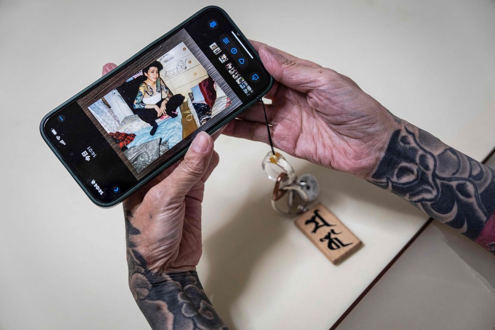A yakuza aposentada Mako Nishimura mostra uma imagem de si mesma quando jovem e integrava o grupo criminoso japonês — Foto: Yuichi Yamazaki / AFP