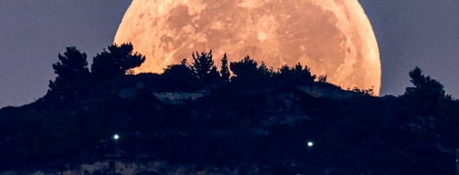 A lua cheia se põe atrás do Monte Gerizim,  na Cisjordânia — Foto: Jaafar ASHTIYEH / AFP