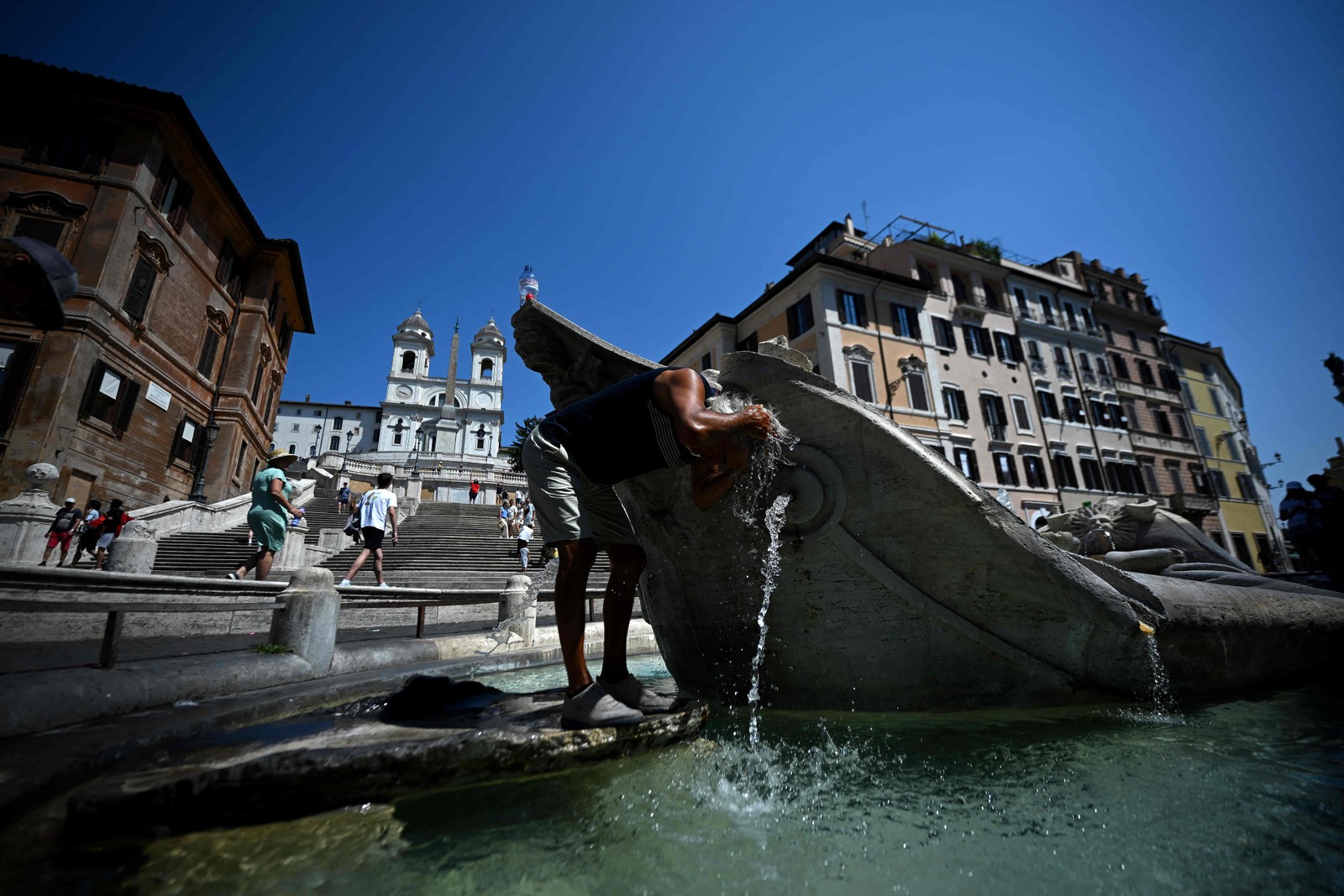 Homem se refresca na fonte Barcaccia, perto da Escadaria Espanhola, durante uma onda de calor em Roma, em 21 de agosto de 2023. — Foto: FILIPPO MONTEFORTE / AFP