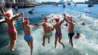 Banhistas participando do tradicional mergulho natalino no Port Vell, em Barcelona — Foto: Josep LAGO / AFP