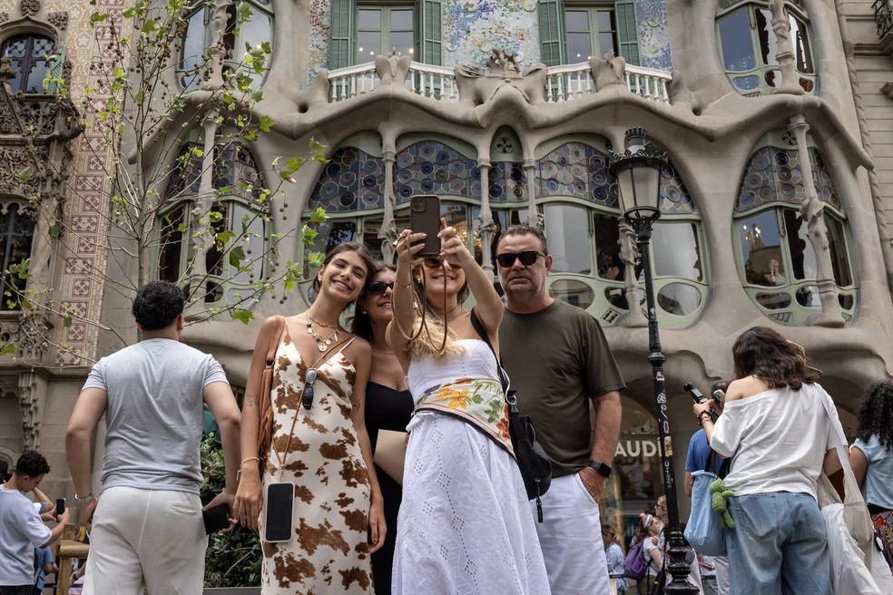 Turistas tiram foto em frente a edifício construído por Antoni Gaudí em Barcelona — Foto: Finbarr O’Reilly / The New York Times