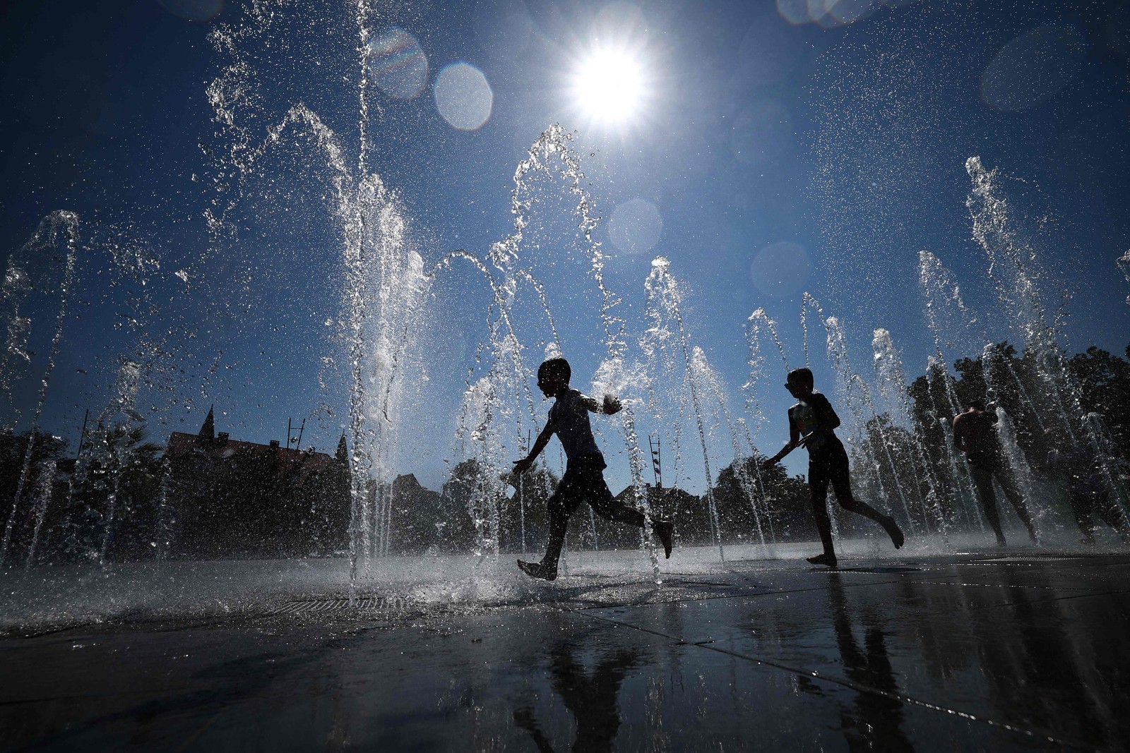 Crianças se refrescam enquanto correm por uma fonte pública em Colmar, na França — Foto: SEBASTIEN BOZON/AFP