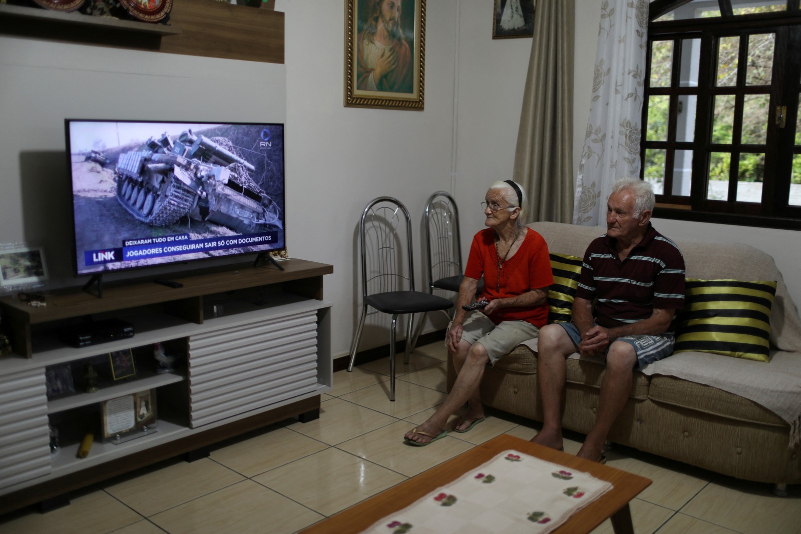 Helena Kachuski, 80, descendente de ucranianos, e seu marido José Petel, 81, assistem ao noticiário na televisão: "Eu sinto muita dor, são mãe com filhos, idosos, muita gente deixando uma boa vida para trás", disse KachuskiReuters