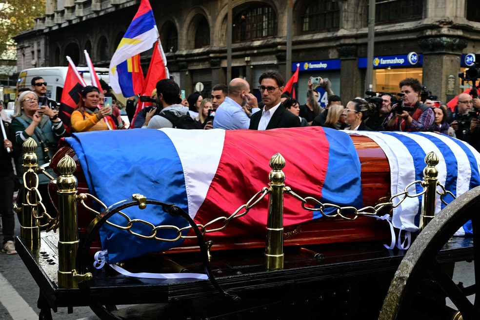 Pessoas aplaudem Pepe Mujica durante cortejo fúnebre pelas ruas de Montevidéu — Foto: Pablo Porciuncula/AFP