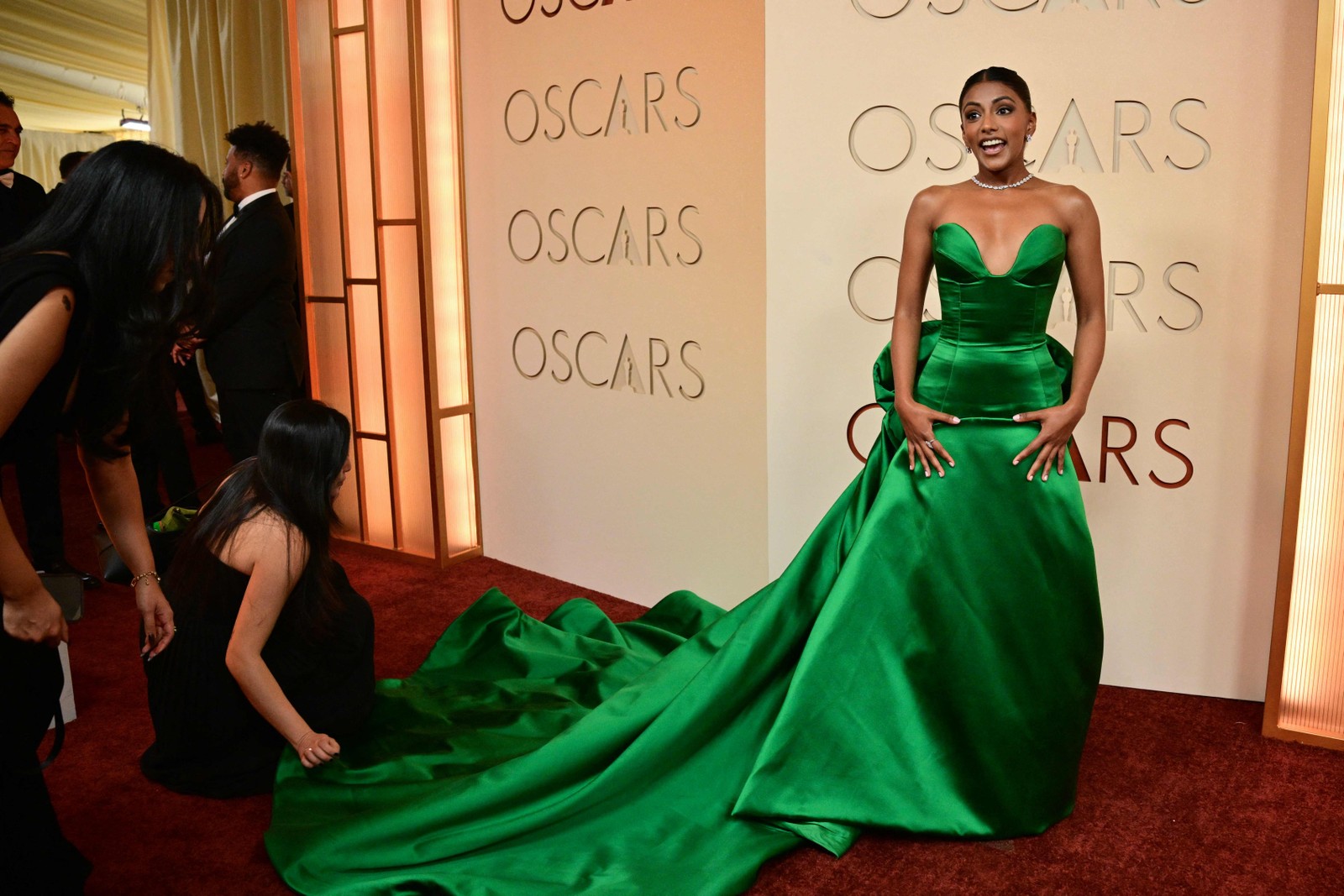 A atriz britânica Charithra Chandran tem o vestido ajustado por um membro da equipe momentos antes de posar para fotos no tapete vermelho do Academy Awards, no Dolby Theatre, em Hollywood, na Califórnia. — Foto: Frederic J. Brown / AFP