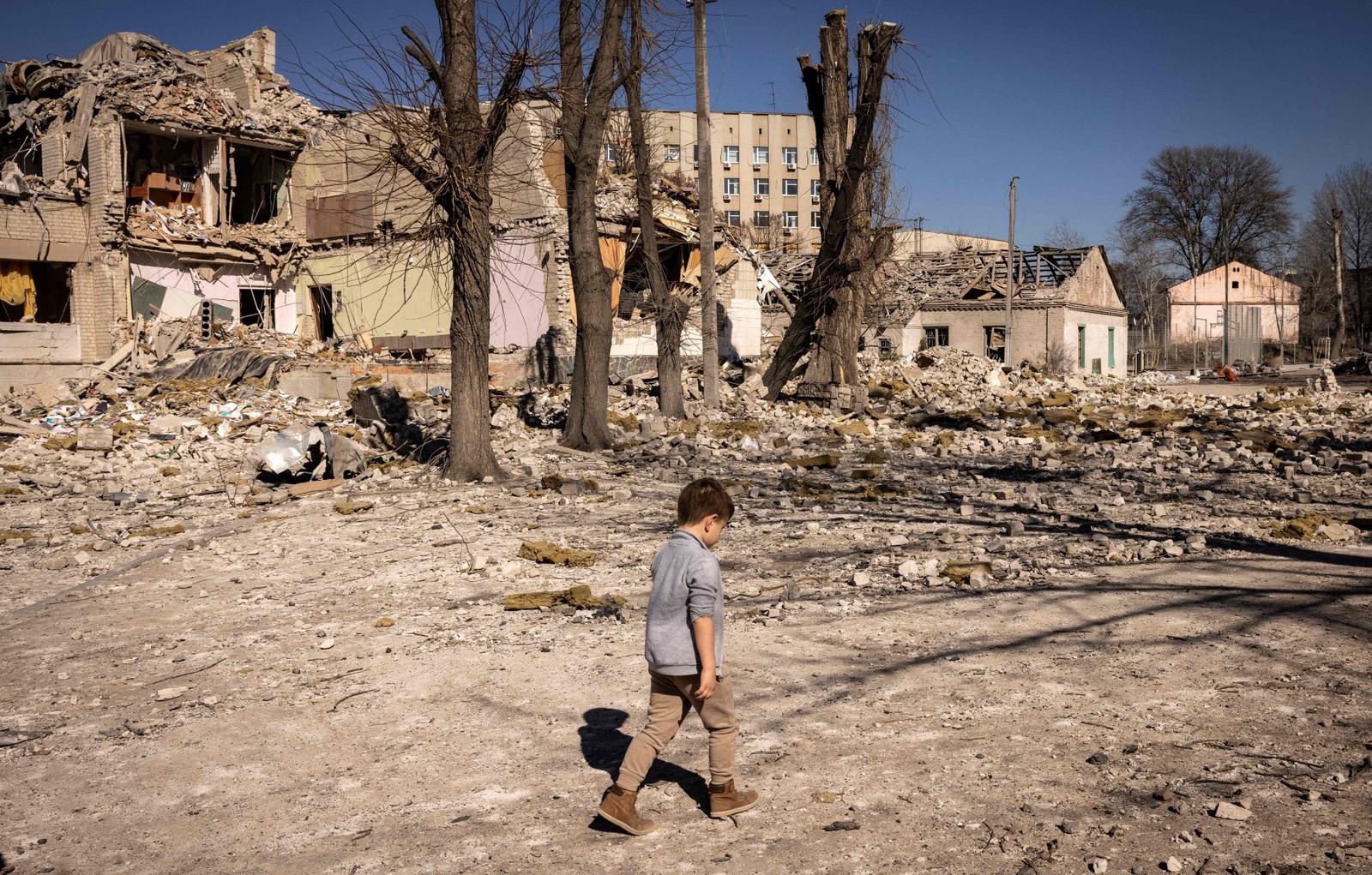 Criança caminha em frente à escola destruída na cidade de Zhytomyr, no Norte ucraniano — Foto: FADEL SENNA/AFP