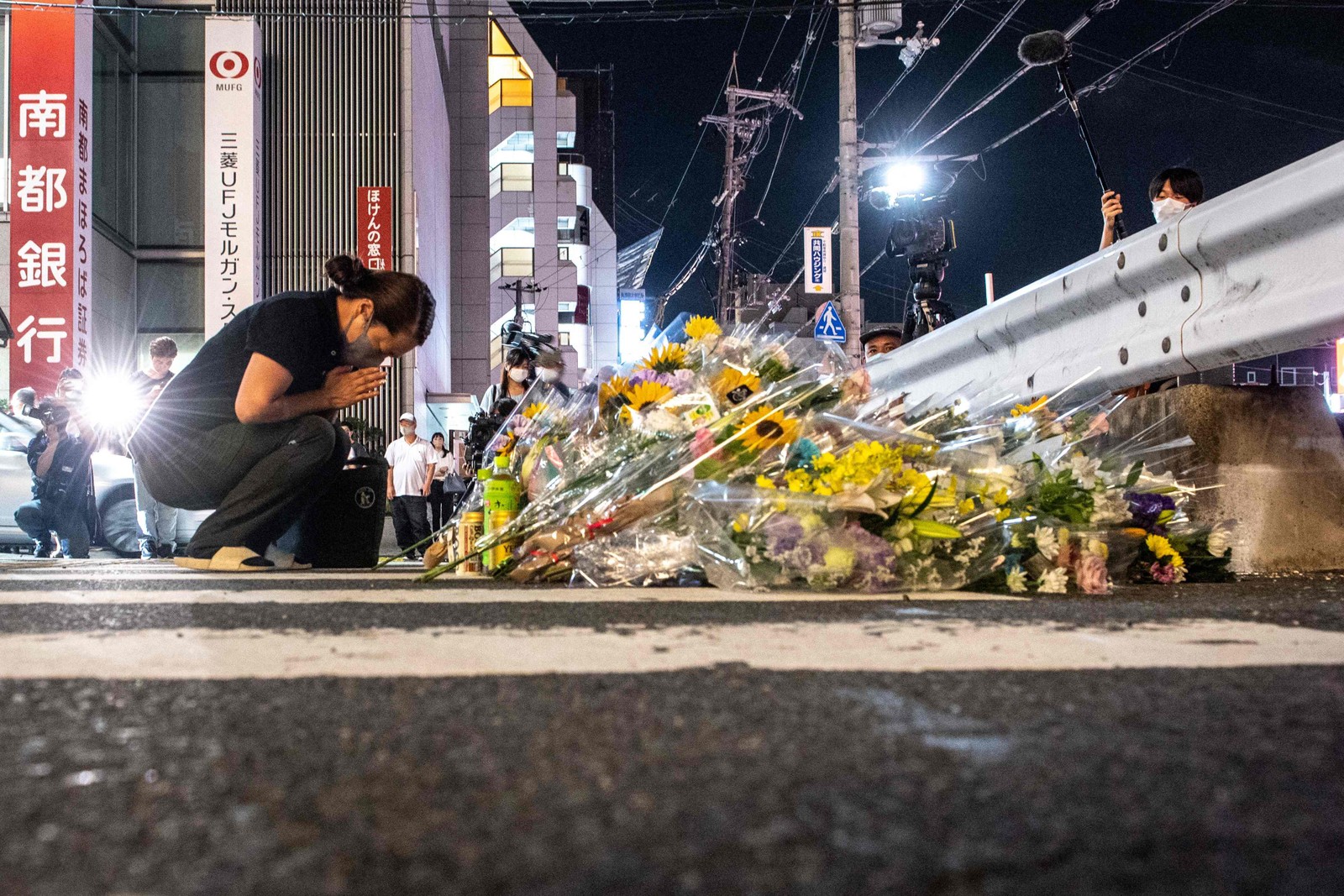 Mulher presta homenagem em memorial improvisado do lado de fora da Estação Yamato-Saidaiji em Nara, onde o ex-primeiro-ministro japonês Shinzo Abe foi baleado no começo do dia — Foto: PHILIP FONG / AFP