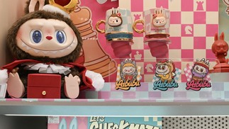 Uma boneca Labubu “não disponível para venda” (à esquerda) e adesivos da Labubu são vistos em uma loja da Pop Mart em Pequim — Foto: Adek Berry/AFP