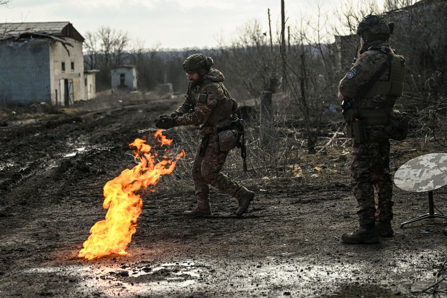 Militares ucranianos acendem fogo com pólvora para se aquecer perto da cidade de Bakhmut, na região de Donbass