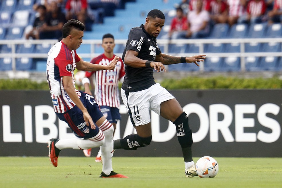 Junior Santos, do Botafogo, tenta passar pela marcação do Junior Barranquilla — Foto: Vitor Silva/Botafogo