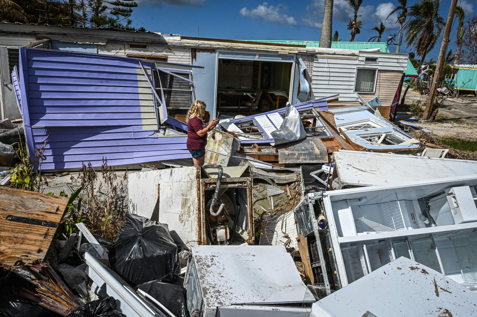 Mulher caminha pelos escombros de uma casa destruída na ilha Matlacha, no condado de Lee, na Flórida — Foto: GIORGIO VIERA/AFP