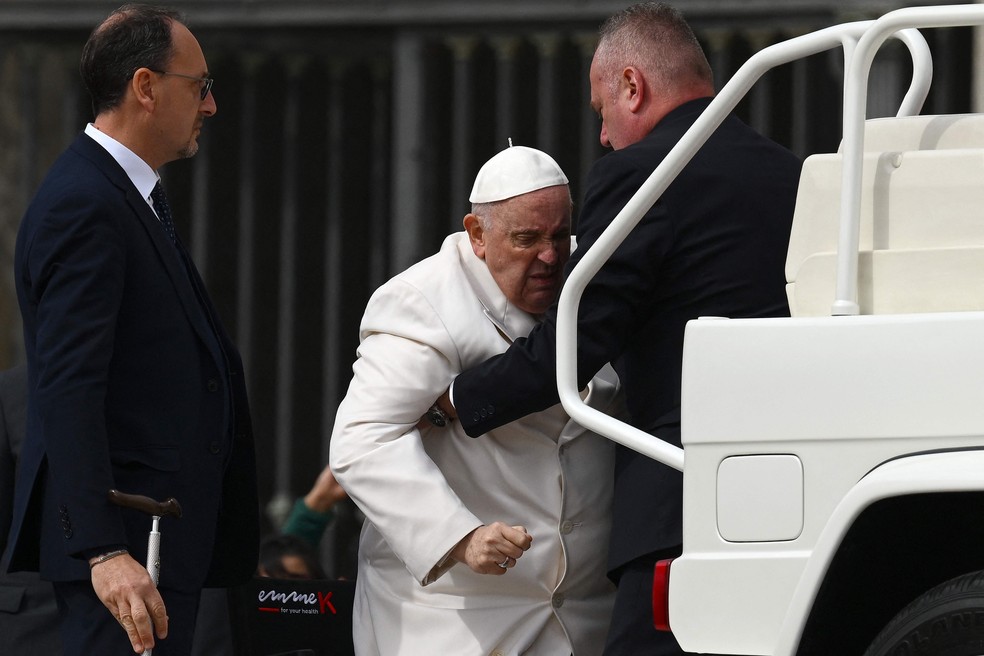 Papa Francisco é ajudado a levantar do papamóvel após audiência geral semanal na praça de São Pedro, no Vaticano — Foto: Vincenzo Pinto/ AFP