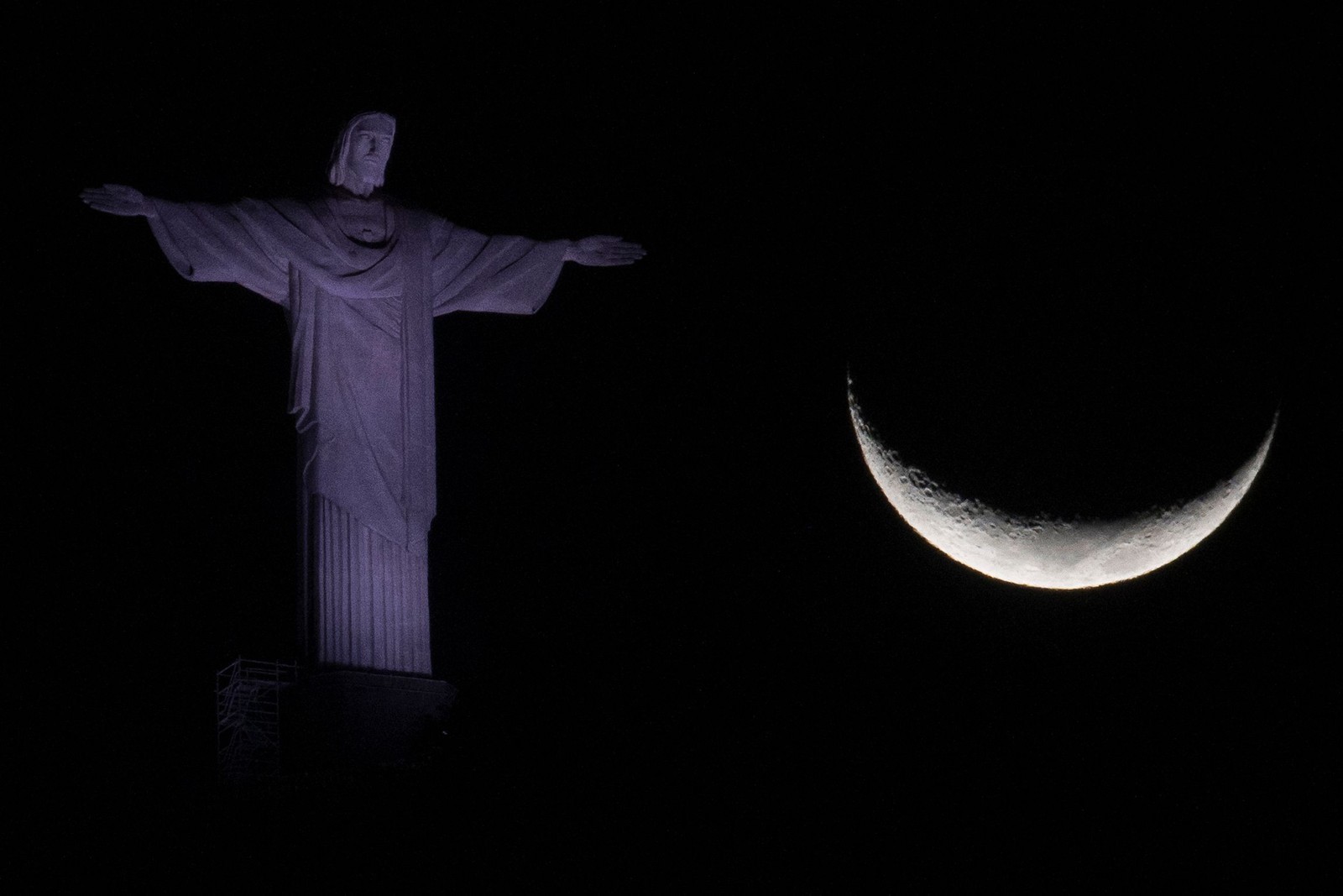 A lua crescente é vista ao lado da estátua do Cristo Redentor no Rio de Janeiro — Foto: MAURO PIMENTEL / AFP