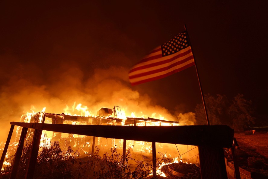 Uma casa queima enquanto um incêndio se espalha na região de Mariposa, Califórnia