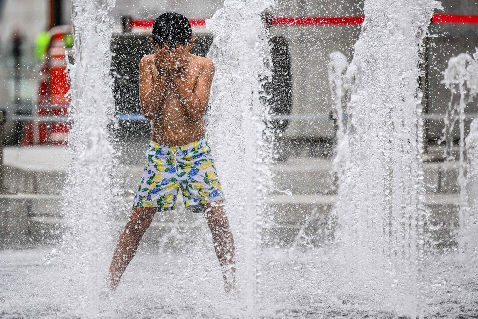 Criança sul-coreana brinca em uma fonte de água no centro de Seul — Foto: ANTHONY WALLACE / AFP