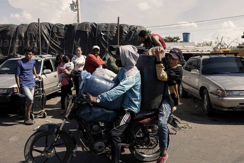 Dois meninos andam de motocicleta carregando tanques cheios de gasolina colombiana para a Venezuela, na cidade fronteiriça de Paraguachón, Colômbia — Foto: Bloomberg