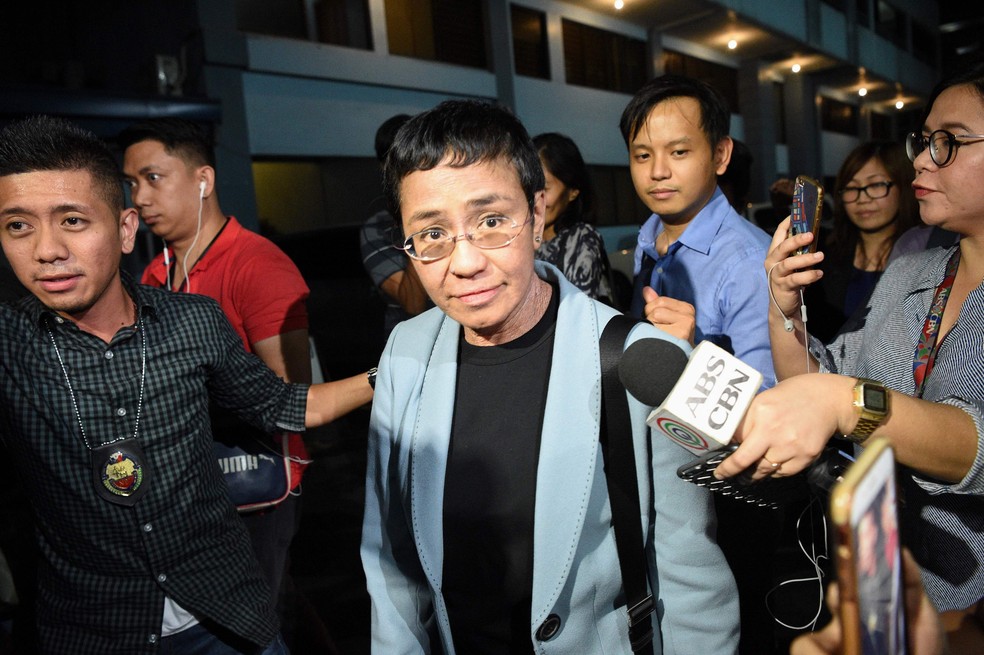 Maria Ressa, jornalista e vencedora do Nobel da Paz, é cercada por repórteres após ser presa em Manila — Foto: TED ALJIBE / AFP