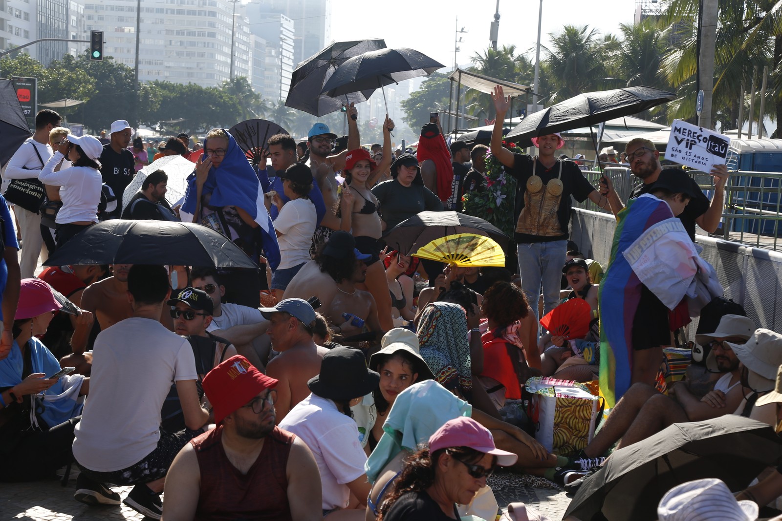 Fã se protegem do calor enquanto aguardam por show de Madonna em Copacabana — Foto: Fabiano Rocha / O Globo