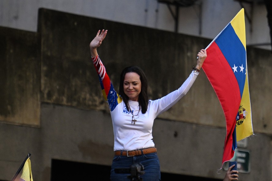 Líder da oposição venezuelana, Maria Corina Machado, agita bandeira nacional durante protesto convocado pela oposição na véspera da posse presidencial de Maduro, em Caracas