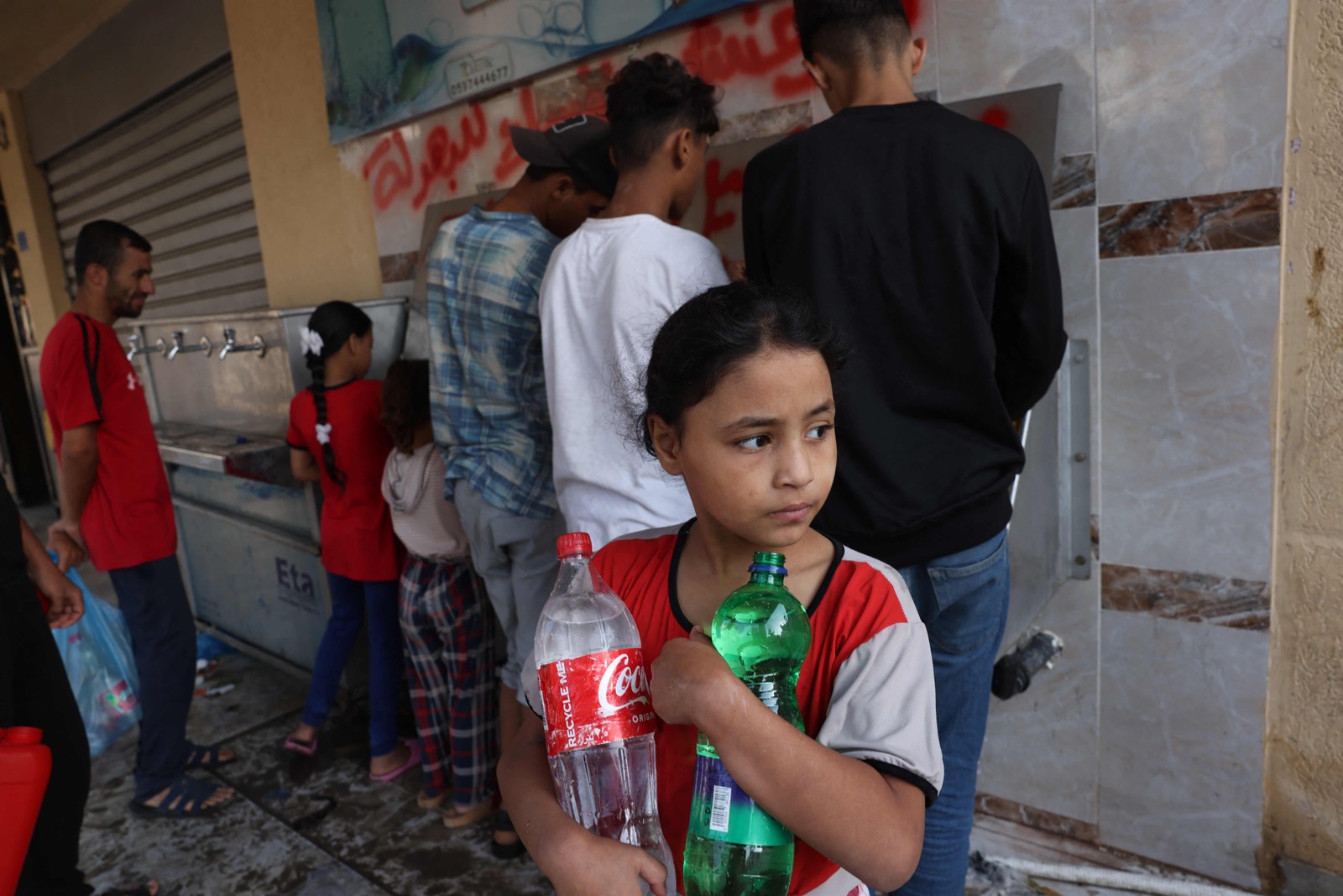 Com guerra entre Israel e Hamas, famílias palestinas estão sem fornecimento de água, luz ou alimentos; na foto, criança busca garrafas de água — Foto: Mohammed Abed/AFP