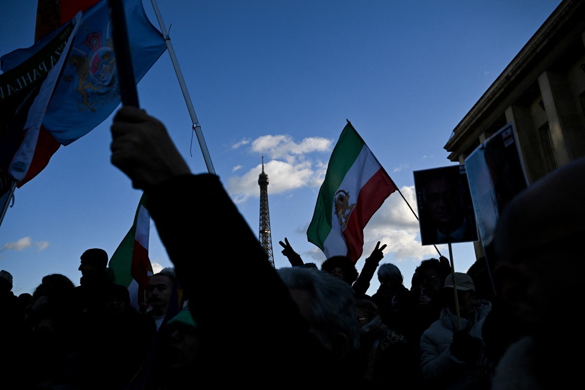 Manifestantes agitam bandeiras do Irã anteriores à Revolução Islâmica de 1979 durante um protesto contra a repressão do regime iraniano aos protestos no centro de Paris, em 4 de janeiro de 2026 — Foto: BLANCA CRUZ / AFP