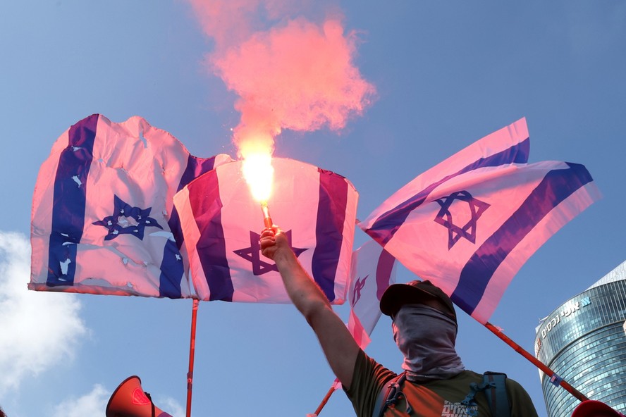 Manifestantes usam sinalizadores durante um 'dia de resistência' para protestar contra o projeto de reforma judicial do governo israelense, em Tel Aviv