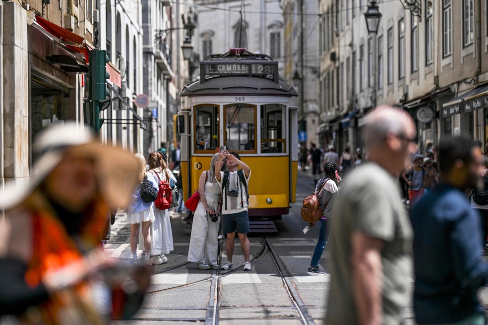 Pedestres tiram foto em frente a vagão de bonde parado em Lisboa — Foto: Patricia de Melo Moreira/AFP