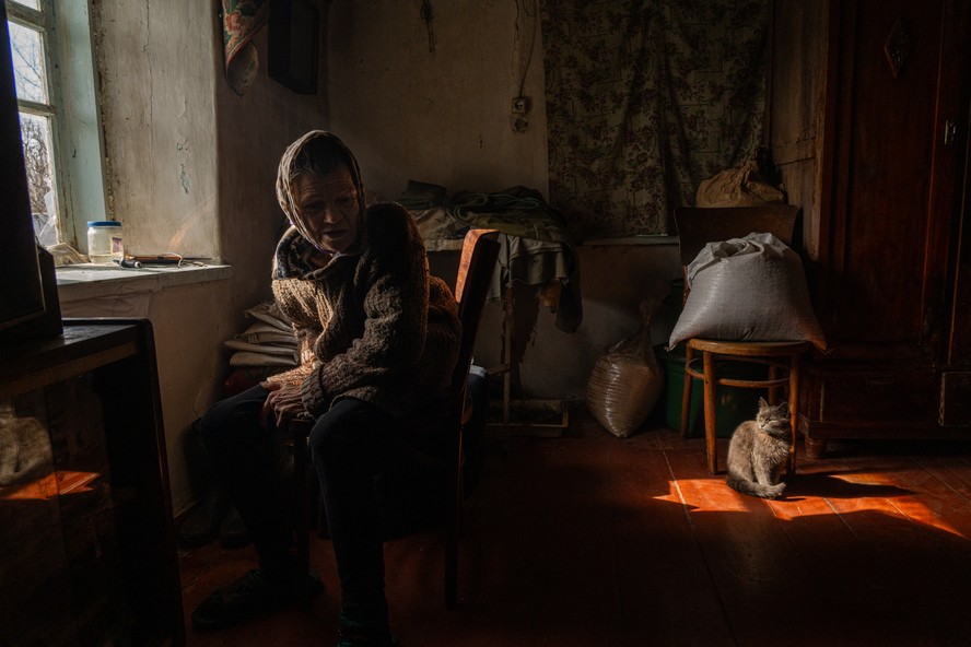 Paraskovya e a sua família decidiram ficar em sua casa mesmo com a guerra chegando cada vez mais perto de sua cidade semi-destruída. A senhora diz estar com medo das explosões constantes, mas conta ter ainda mais medo de se tornar uma refugiada. Foto tirada em Ocheretyno, Oblast de Donetsk, Ucrânia