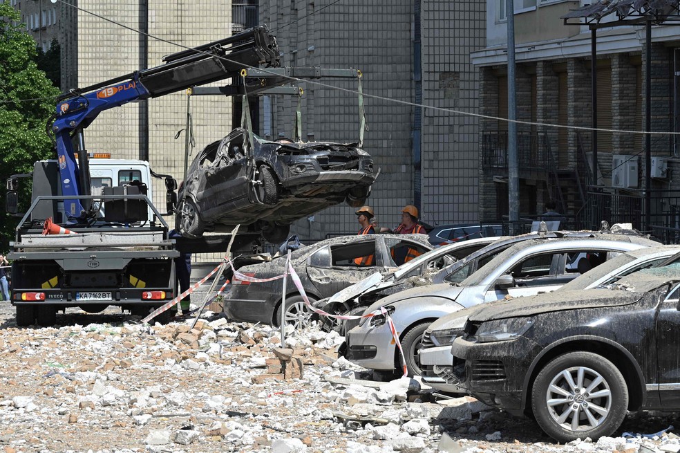 Carros são rebocados de estacionamento de prédio residencial atingido por ataques russos em Kiev — Foto: Genya SAVILOV / AFP
